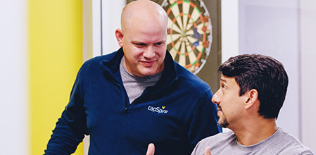 Two men talking with a dartboard