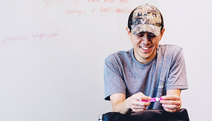 A man smiling over a pen