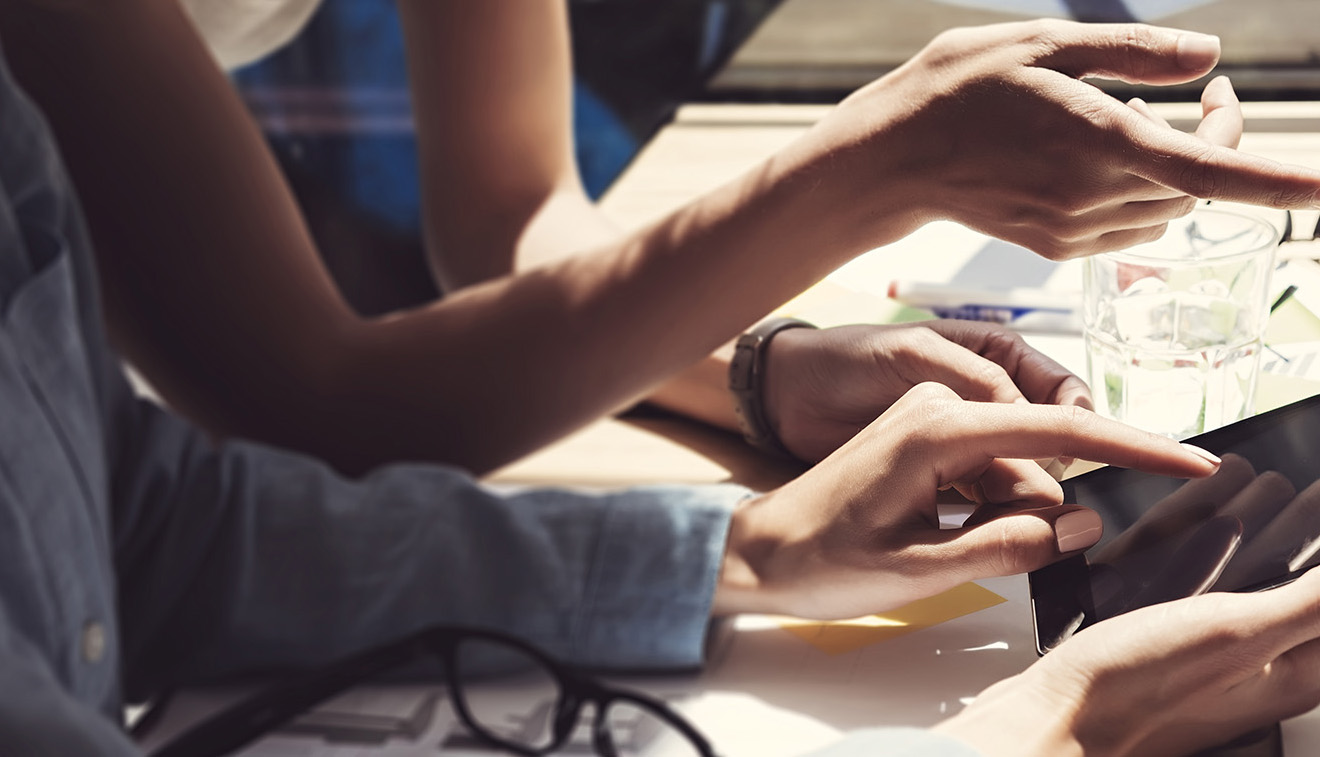 Girl Showing Screen Digital Tablet Hand.Project Managers Researching Process.Business Team Working Startup modern Office.Analyze market stock.Using electronic devices,papers,notes wood table.Blurred