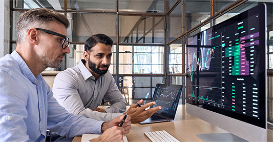 Two men talking about the graphs on the screen
